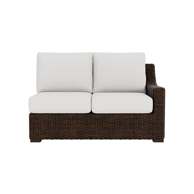 Wicker outdoor sofa with white cushions on a white background