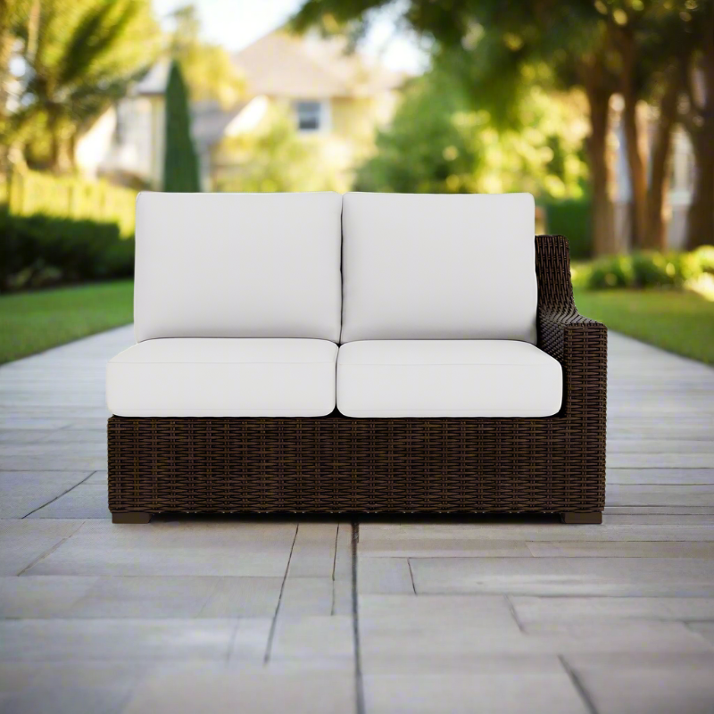Brown wicker outdoor sofa with white cushions on a patio