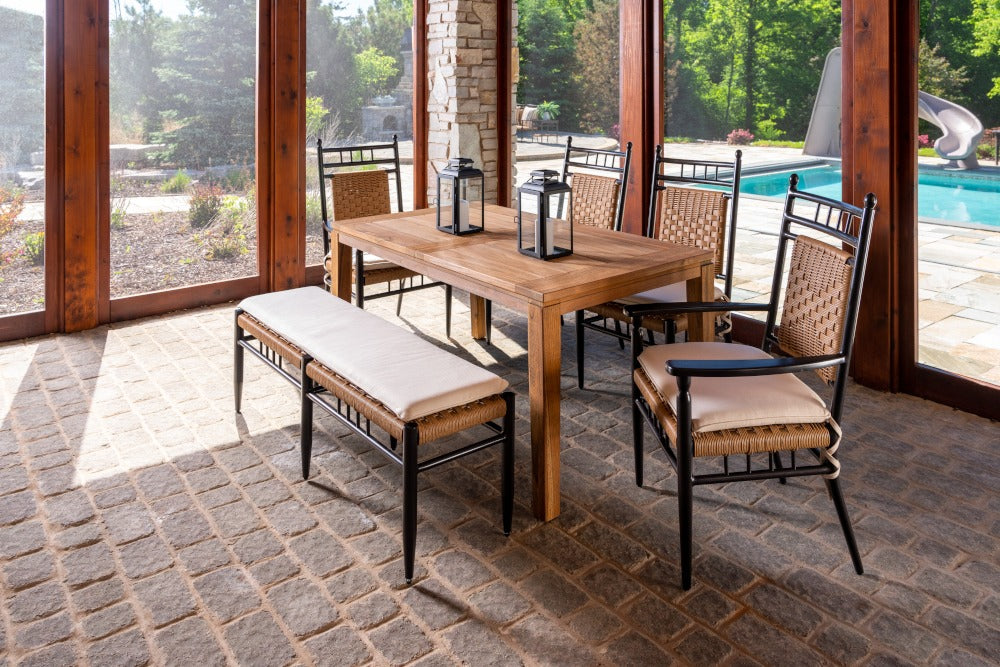 Outdoor dining set with wooden table and chairs on a patio with pool view