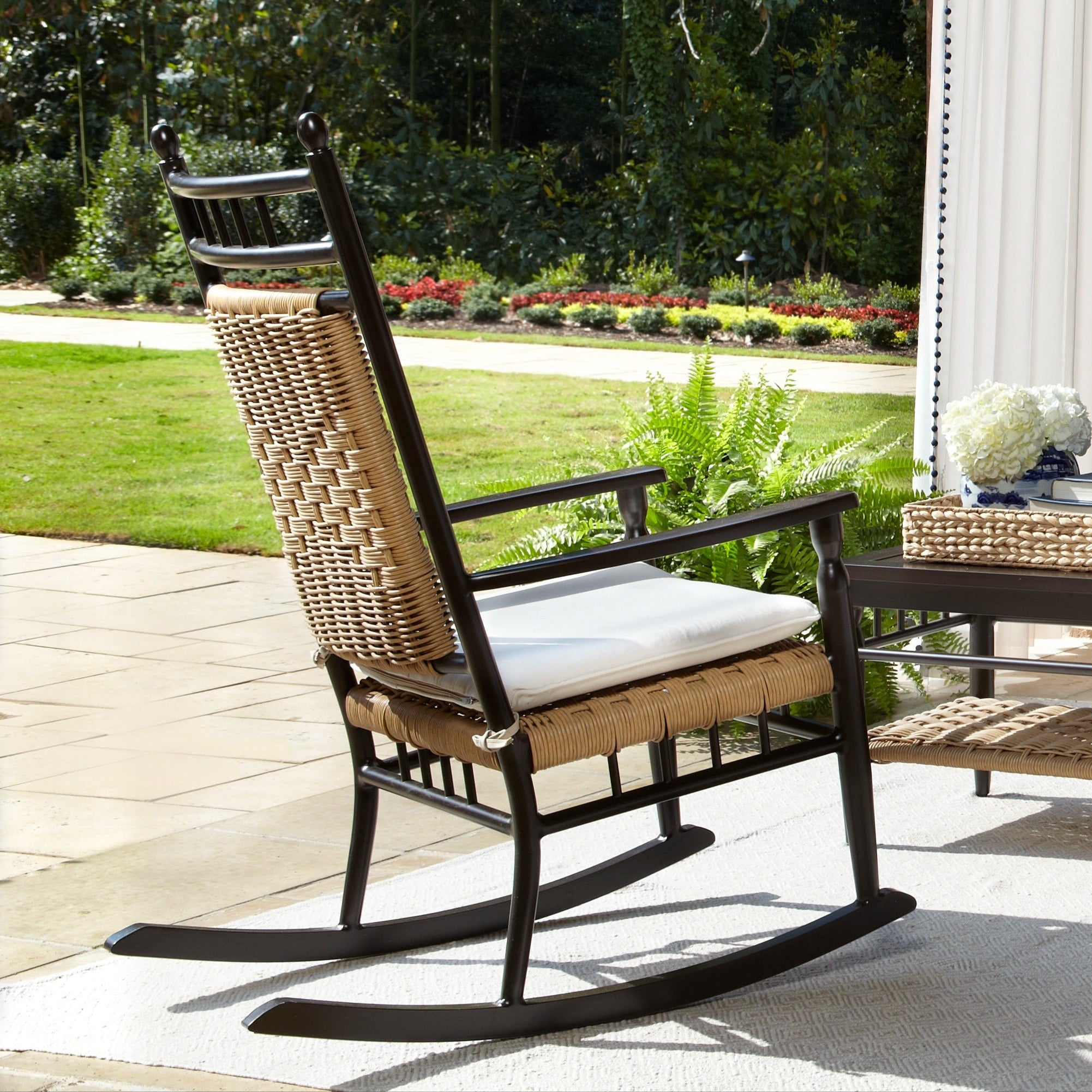 Outdoor patio set with chairs, table, and cushions on a covered patio with brick archway.