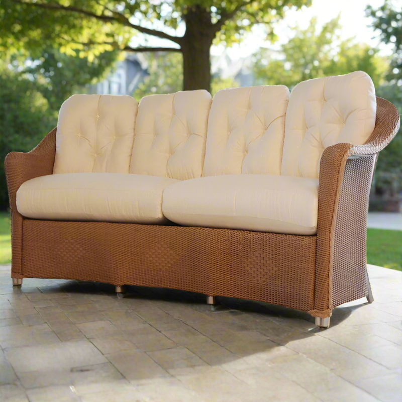 Brown wicker outdoor sofa with beige cushions on a patio