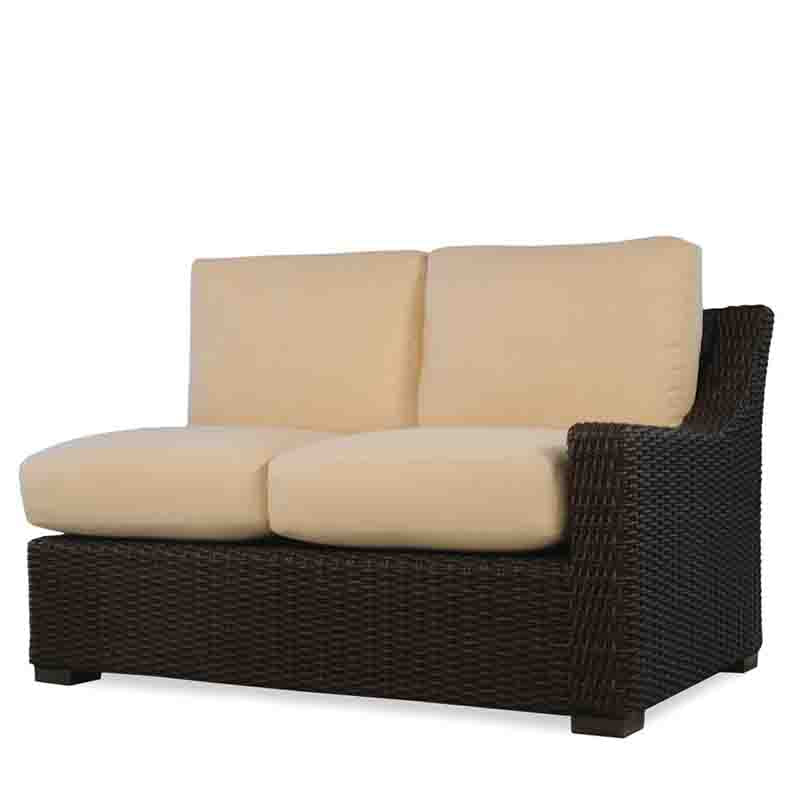 Wicker outdoor loveseat with beige cushions on a white background