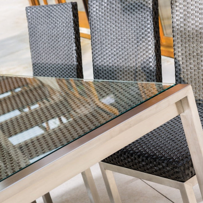 Glass dining table with wicker chairs on a patio