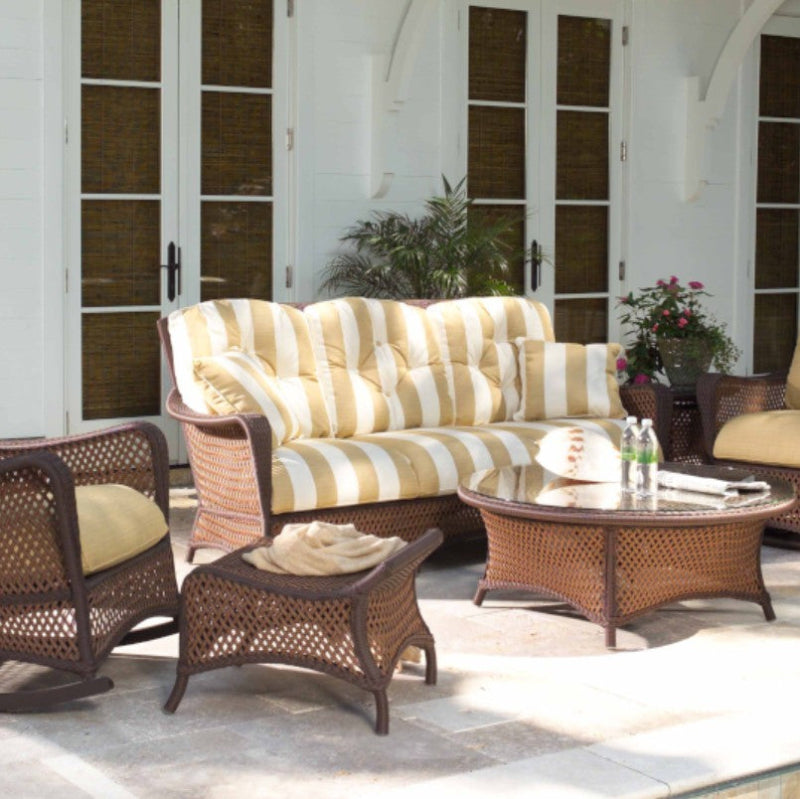 Outdoor patio set with wicker furniture and striped cushions on a patio.