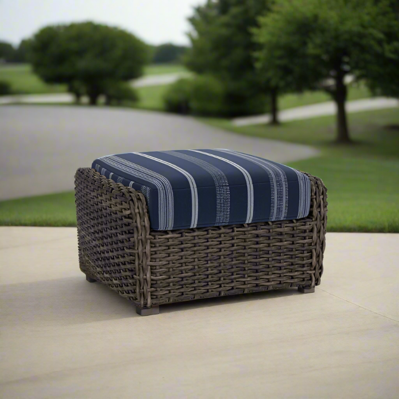 Wicker ottoman with a blue striped cushion on a patio