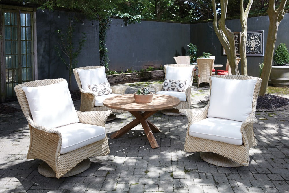 Outdoor patio set with wicker chairs and a wooden table on a stone patio.