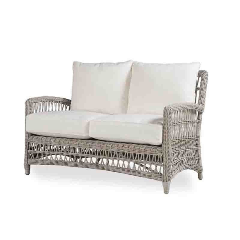 Wicker outdoor sofa with white cushions on a white background