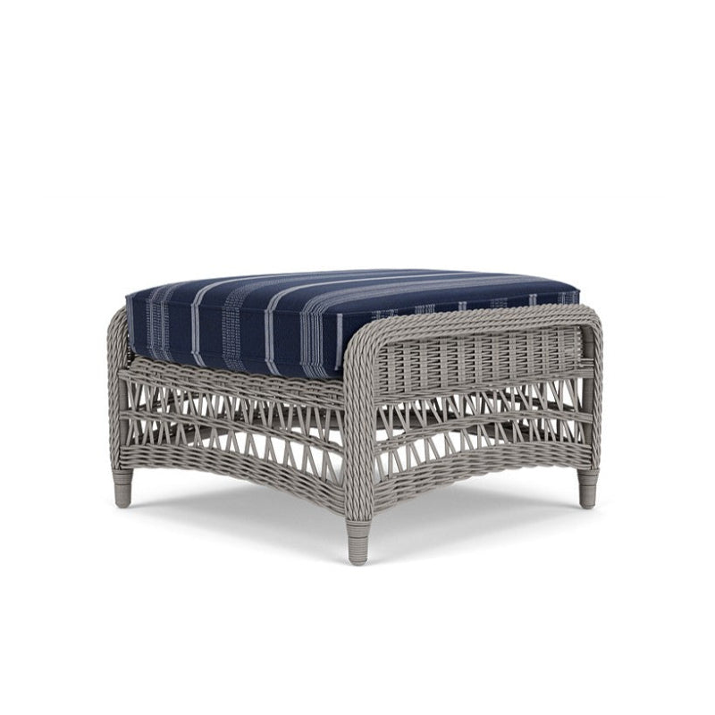 Wicker ottoman with a blue cushion on a white background