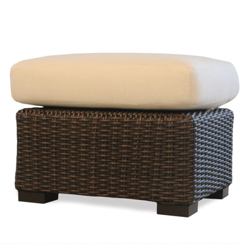 Wicker ottoman with beige cushion on a white background