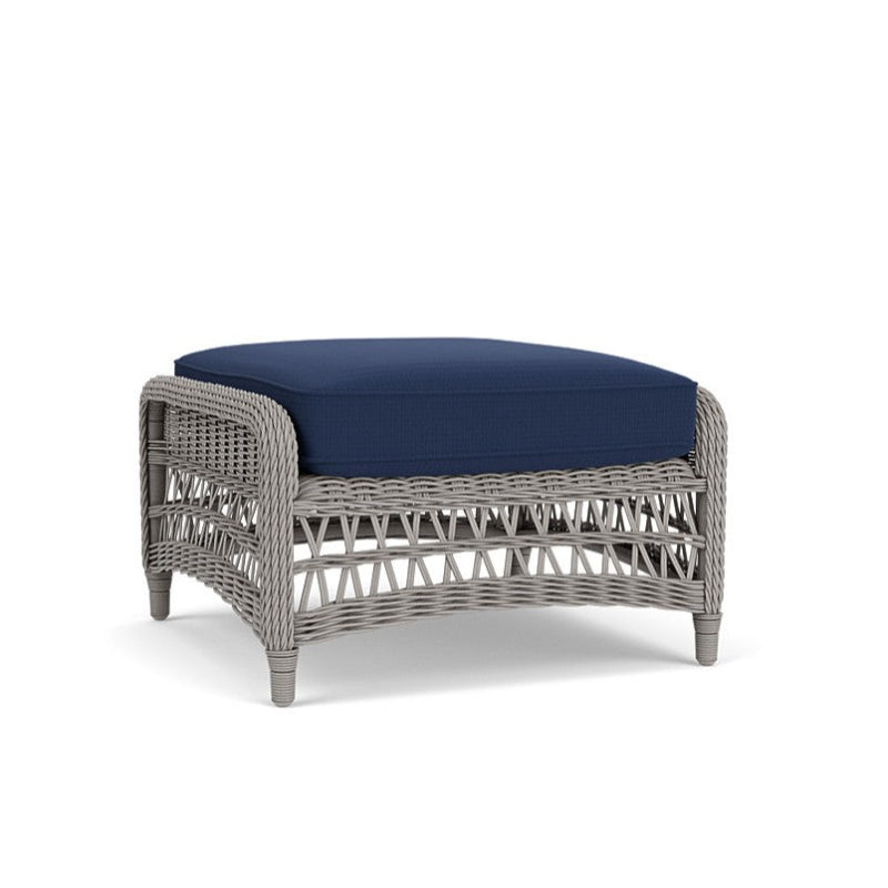 Wicker ottoman with a navy cushion on a white background