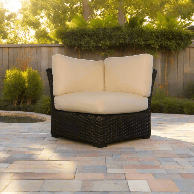 Wicker outdoor loveseat with beige cushions on a patio