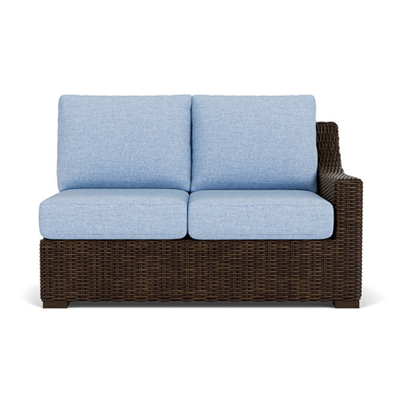Outdoor sofa with wicker frame and light blue cushions on a white background