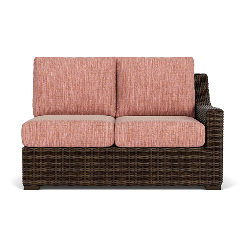 Outdoor sofa with pink cushions and wicker frame on a white background