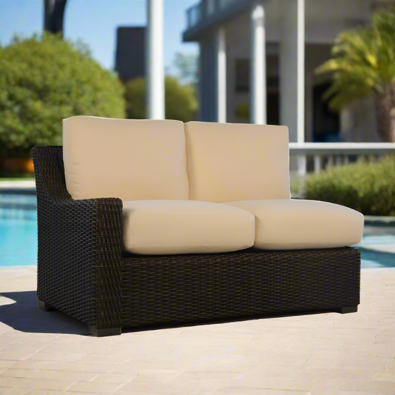 Beige cushioned outdoor loveseat with black frame by a poolside.