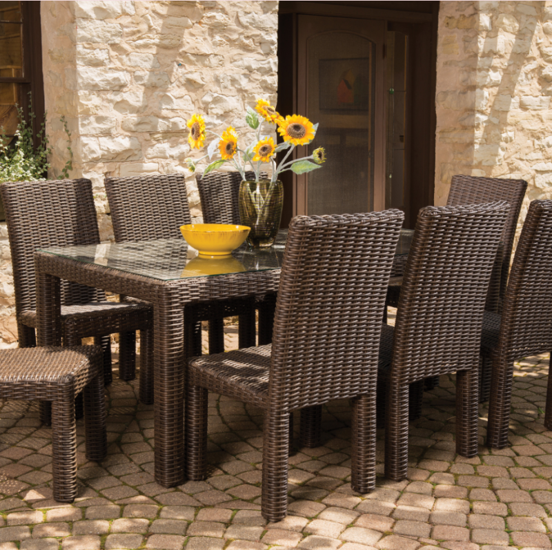 Outdoor dining set with a table and chairs in front of a stone building.