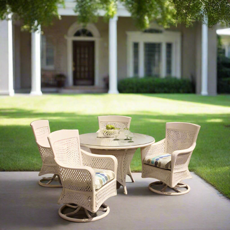 White wicker outdoor furniture set with a table and chairs on a patio overlooking water.