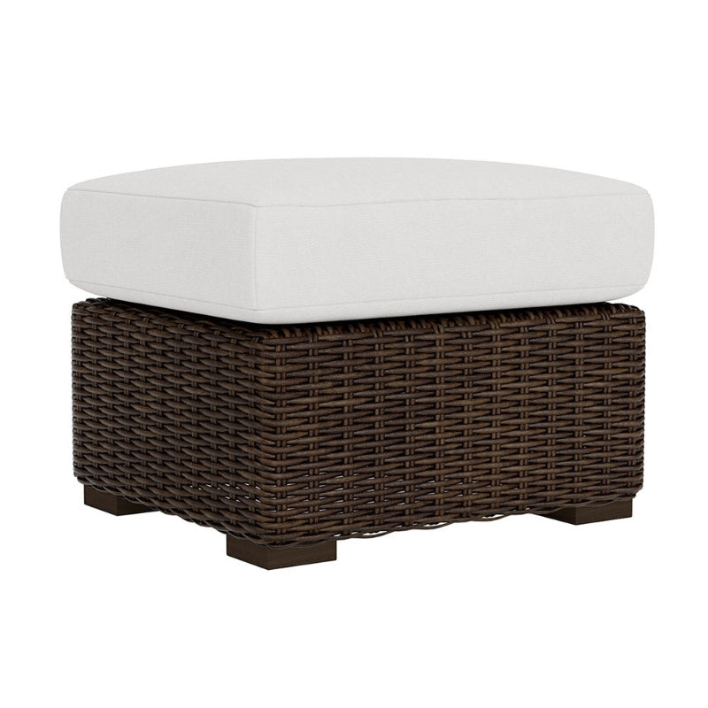 Wicker ottoman with a white cushion on a white background