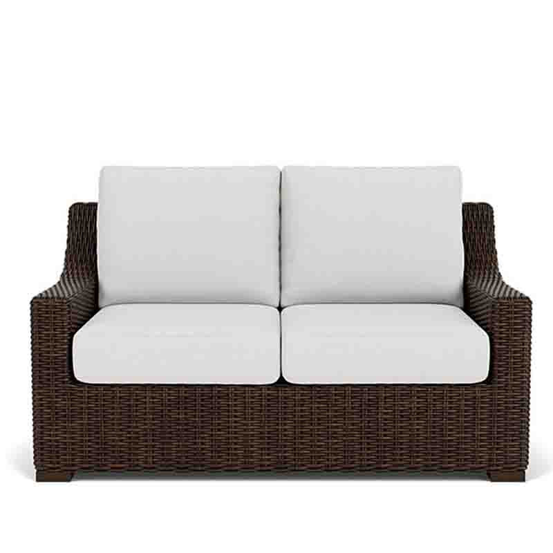 Wicker outdoor sofa with white cushions on a white background