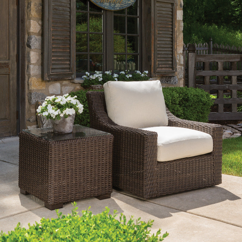 Outdoor patio set with wicker chair and table on a patio area.