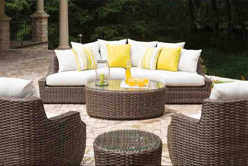 Outdoor patio furniture set with white and yellow cushions on a patio.