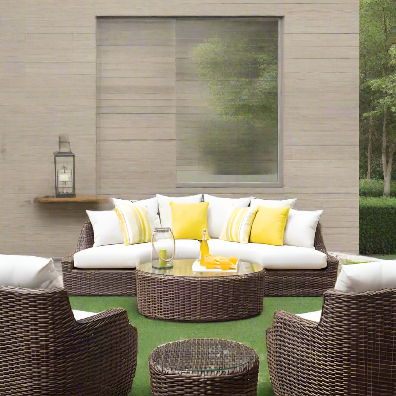 Outdoor patio furniture set with wicker chairs, sofa, and ottoman on a green lawn.