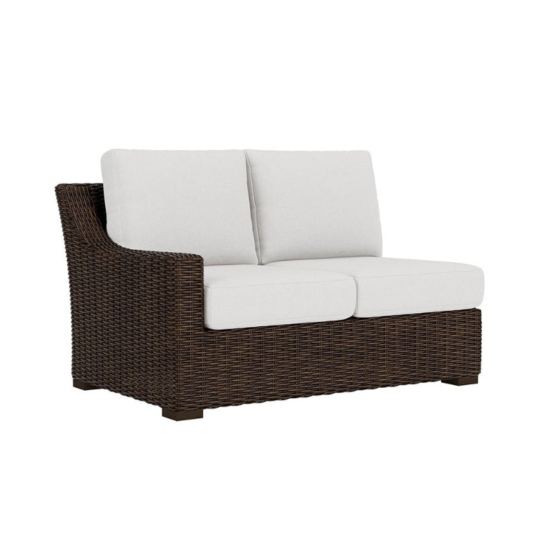 Brown wicker outdoor sofa with white cushions on a white background