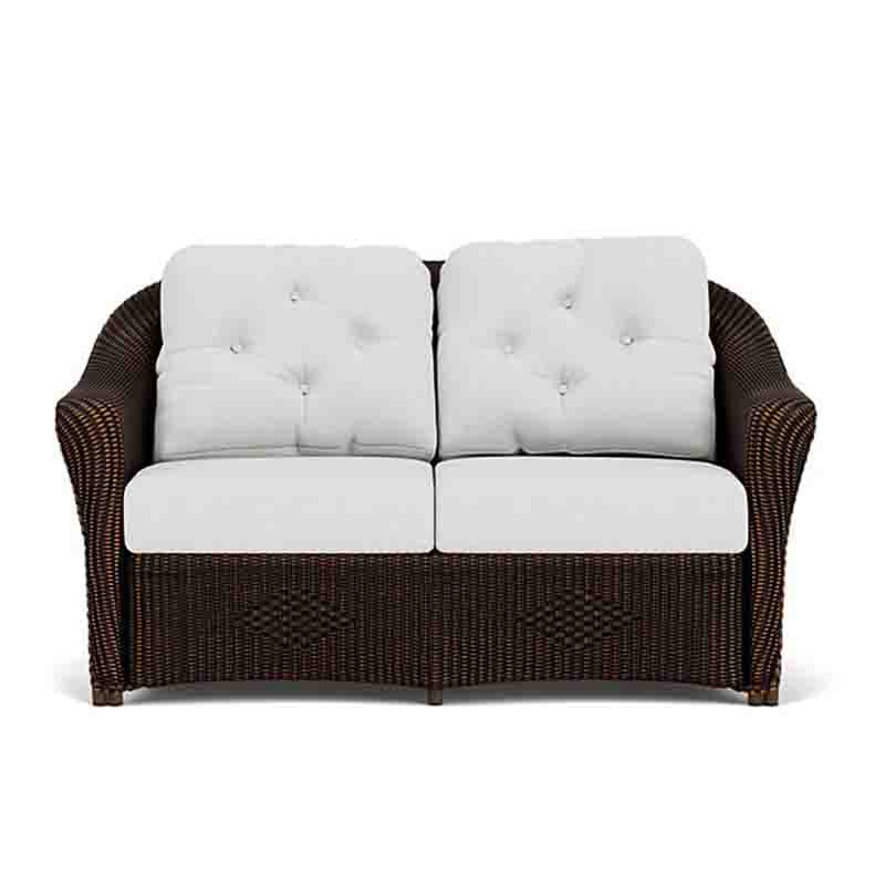 Wicker loveseat with white cushions on a white background