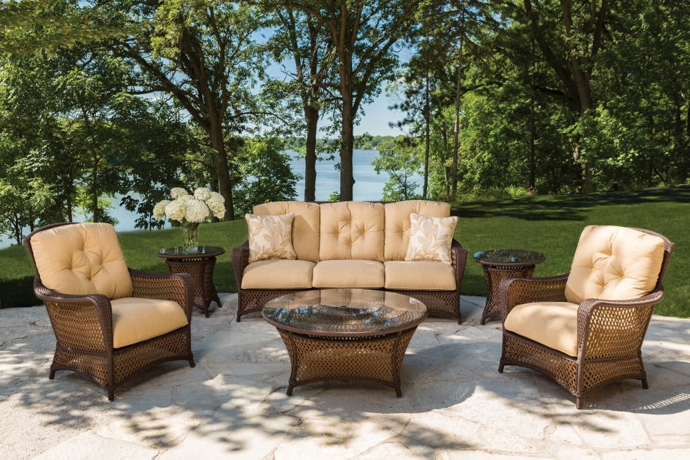 Outdoor patio set with beige cushions and wicker furniture in a scenic setting.