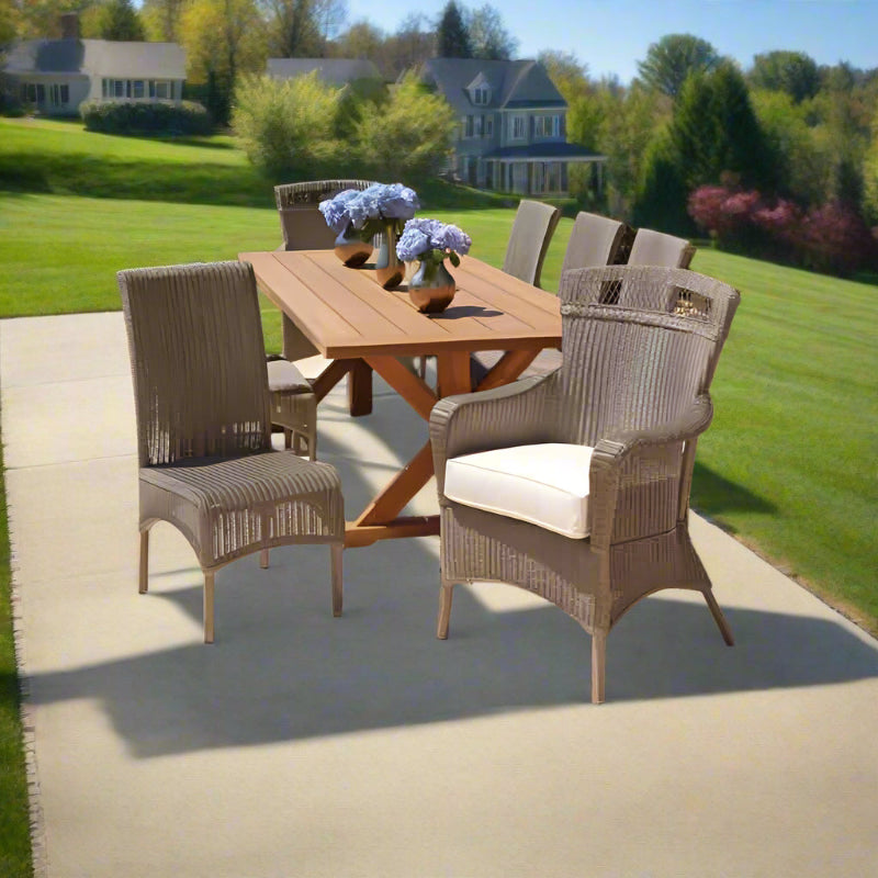 Outdoor dining set with wooden table and wicker chairs on a patio.