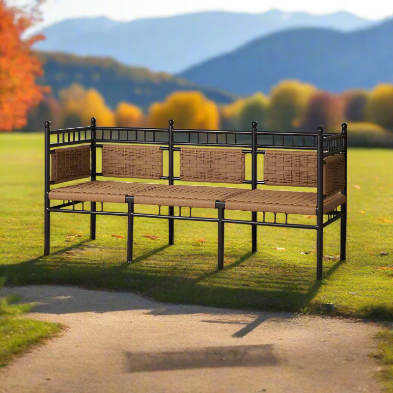 Wicker bench with metal frame in a park setting with trees and mountains in the background