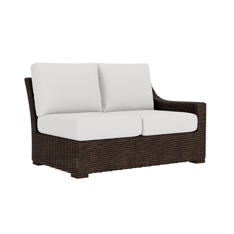 Wicker outdoor sofa with white cushions on a white background