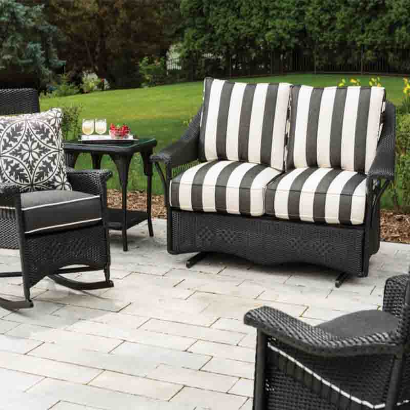 Outdoor patio furniture set with black and white striped cushions on a stone patio.