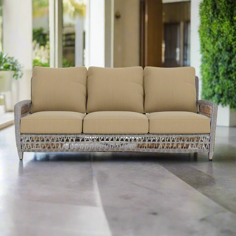 Beige outdoor sofa with wicker frame on a patio