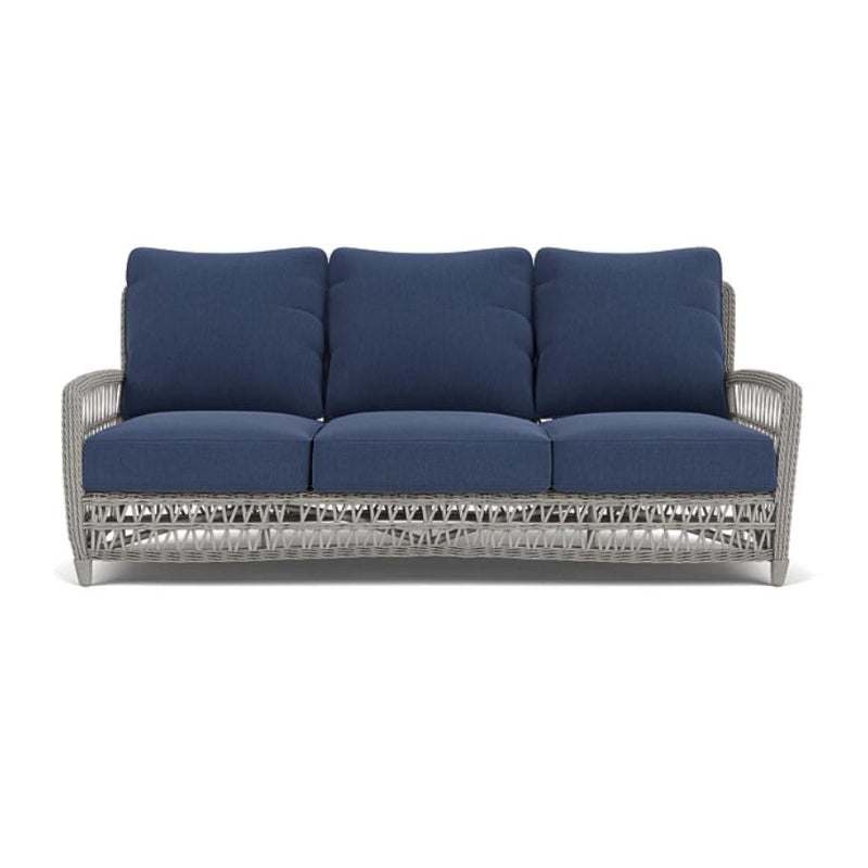 Outdoor sofa with blue cushions and a wicker frame on a white background