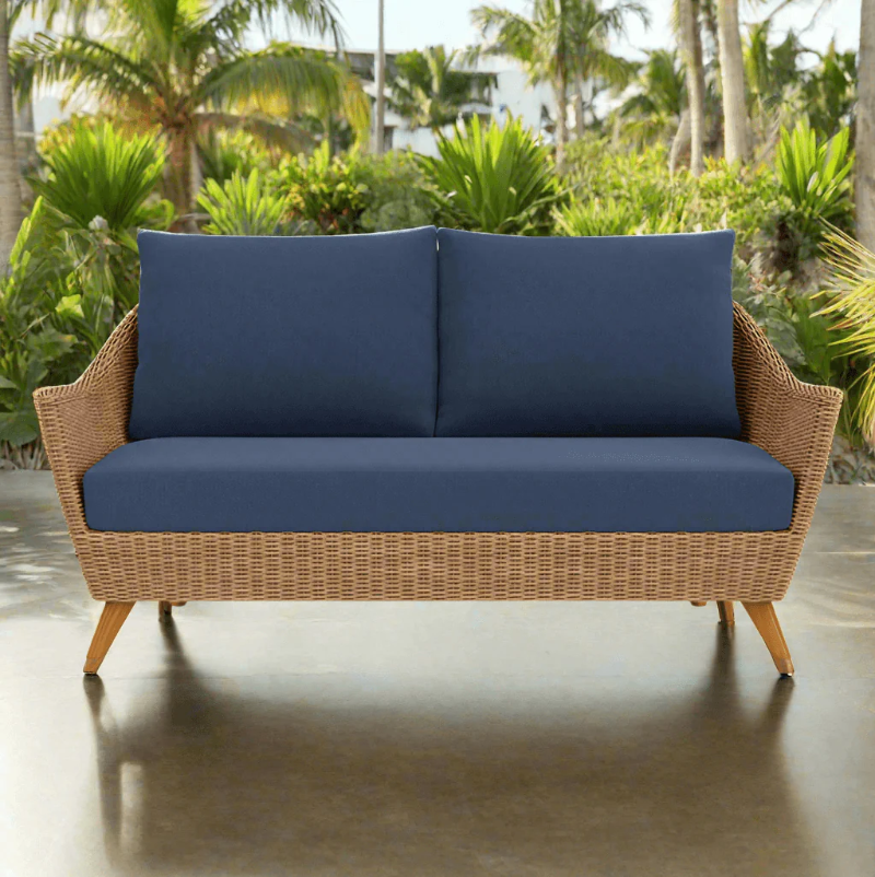 Wicker outdoor sofa with blue cushions in a tropical setting