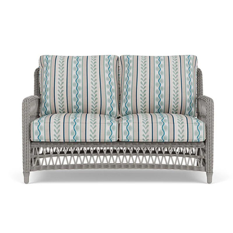 Wicker loveseat with striped cushions on a white background
