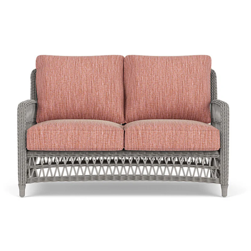 Two-seater outdoor sofa with pink cushions and gray wicker frame on a white background