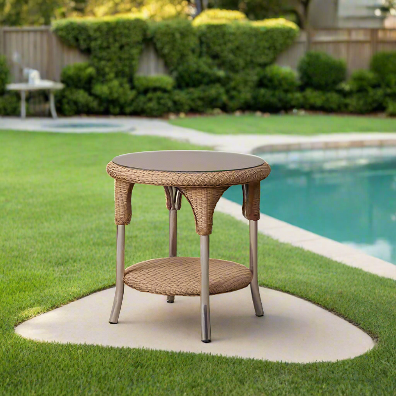 Round wicker side table with a dark top on a patio by a pool