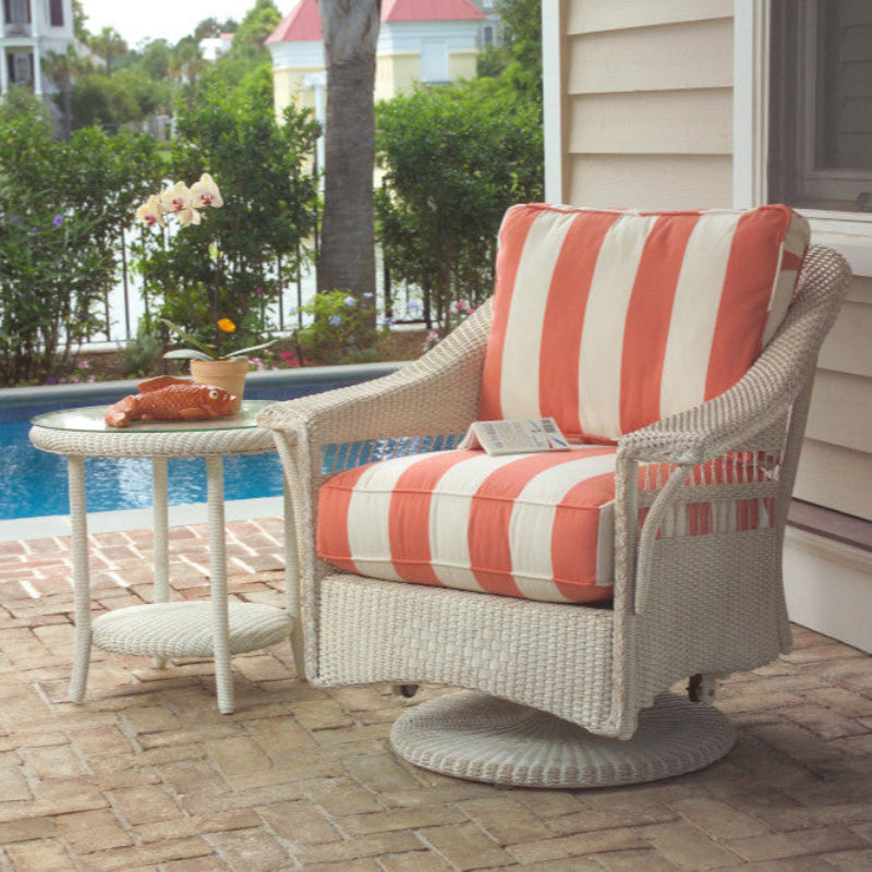 Wicker chair with striped cushions on a patio by a pool