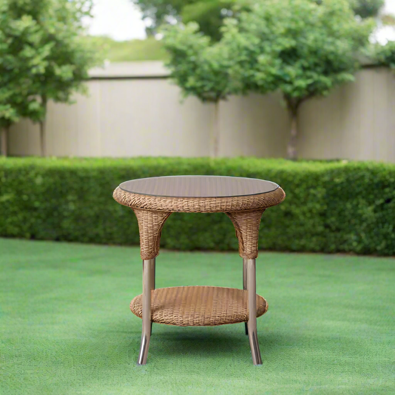 Wicker side table on a green lawn with trees and a white wall in the background