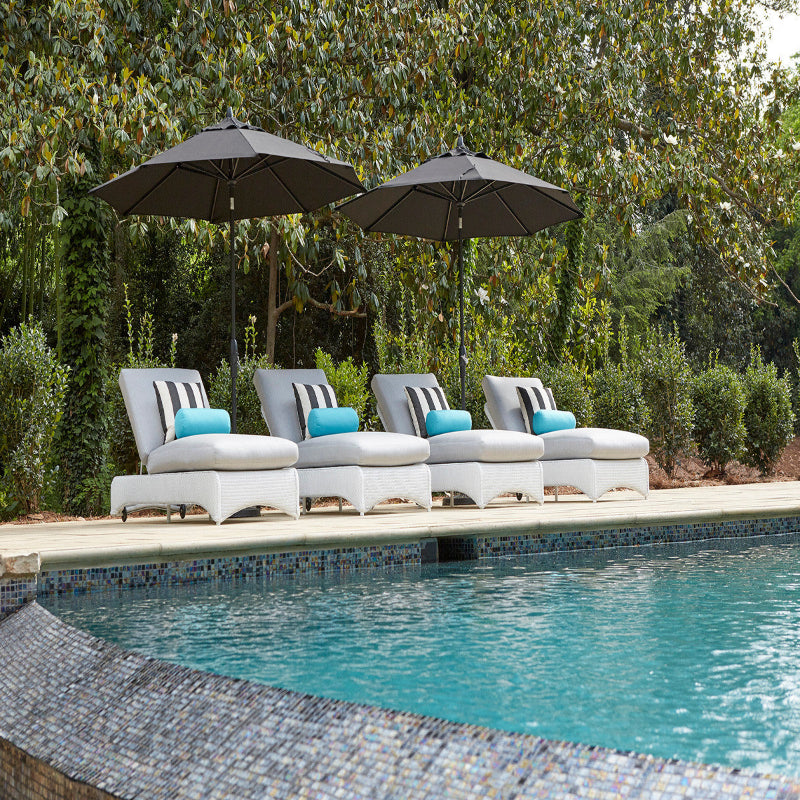 Poolside area with lounge chairs and umbrellas under a tree