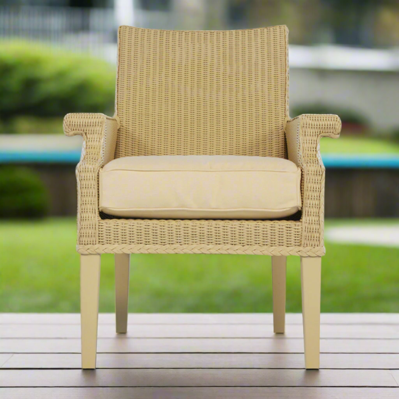 Beige wicker chair with cushion on a wooden deck