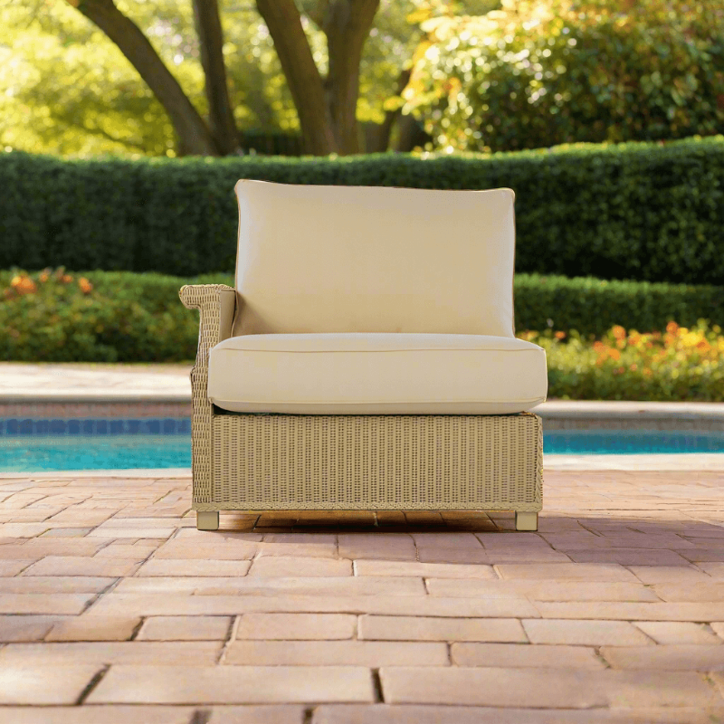 Beige wicker chair with cushion on a patio by a pool