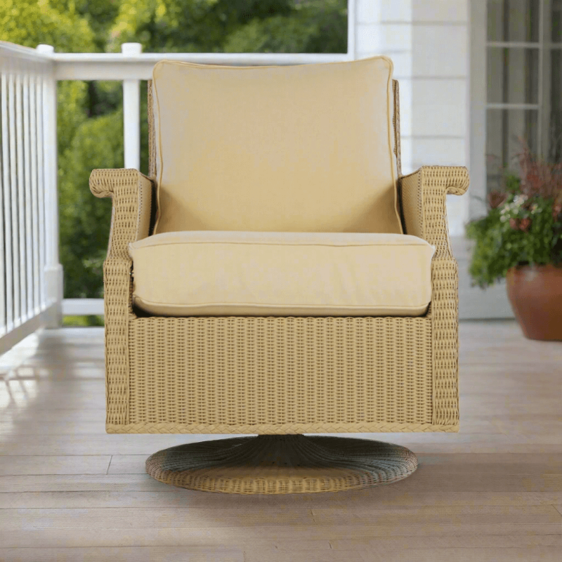 A beige Lloyd Flanders wicker swivel rocker lounge chair with cushions on a porch.