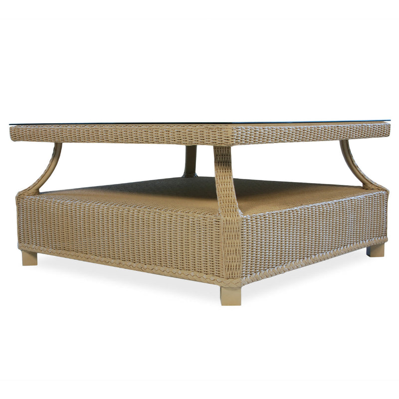 A square wicker cocktail table with a beige color, featuring a textured weave and a visible aluminum frame.