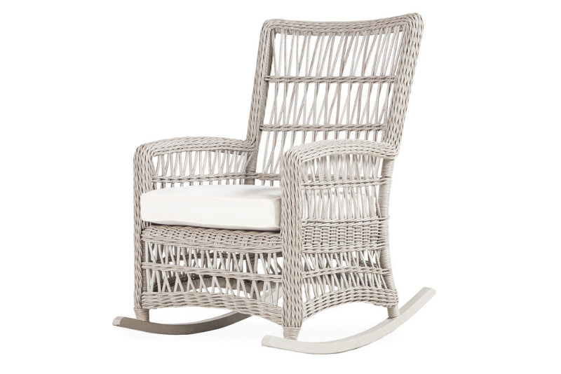A beige wicker high back porch rocker with a teak wood top and white cushioning.