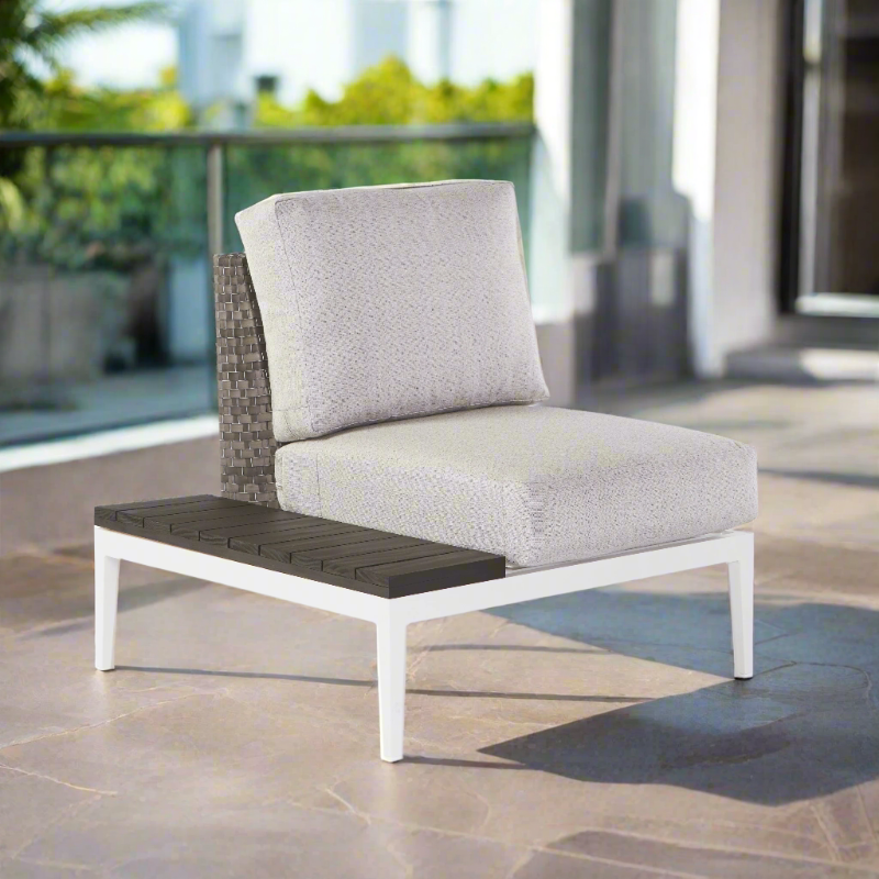 Outdoor patio chair with gray cushion and wooden armrest on a stone patio.