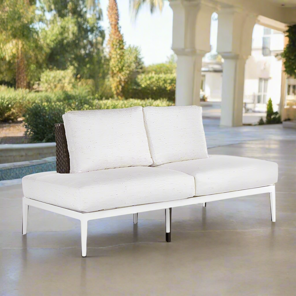 White outdoor sofa with cushions on a patio near a pool