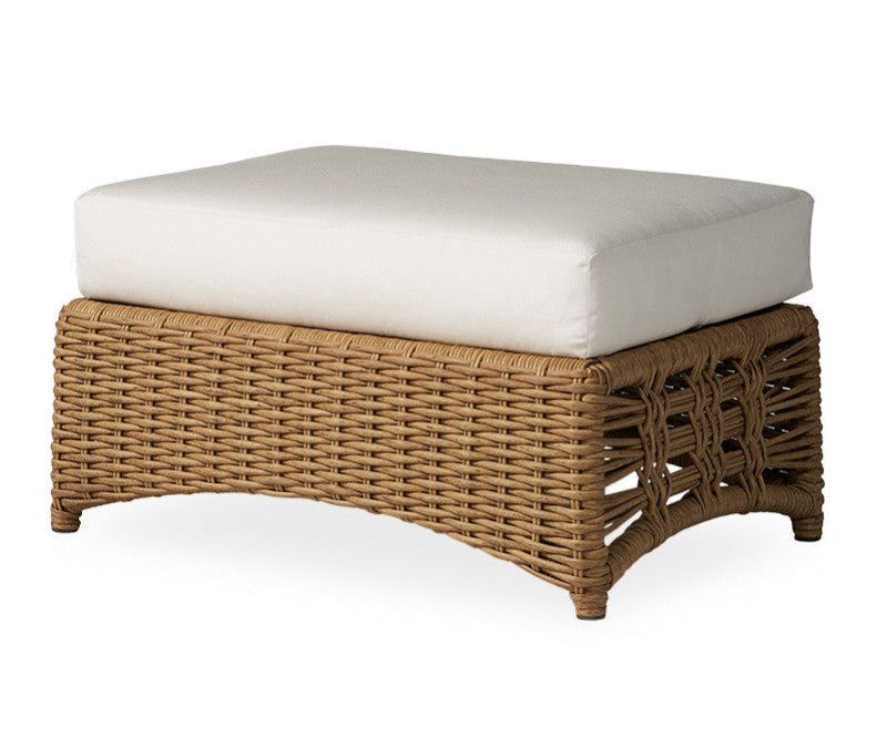 Wicker ottoman with a white cushion on a white background