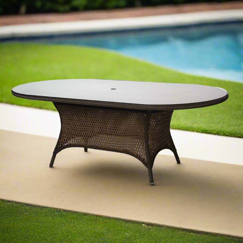 Round outdoor table with wicker design on a patio near a pool